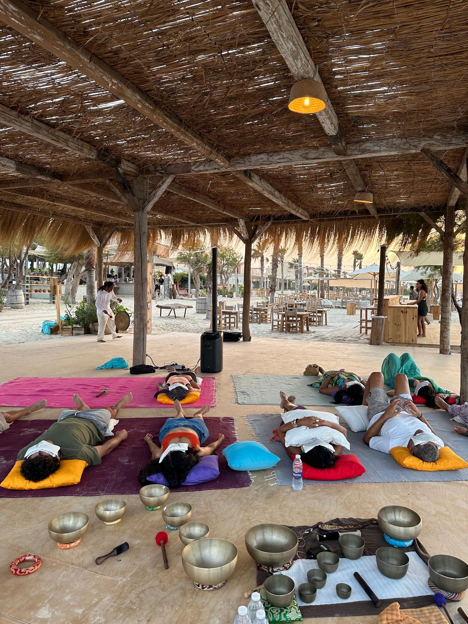 Group sound healing journey with participants lying down surrounded by singing bowls